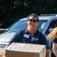 GVSU Alumna smiles as she carries in a big cardboard box